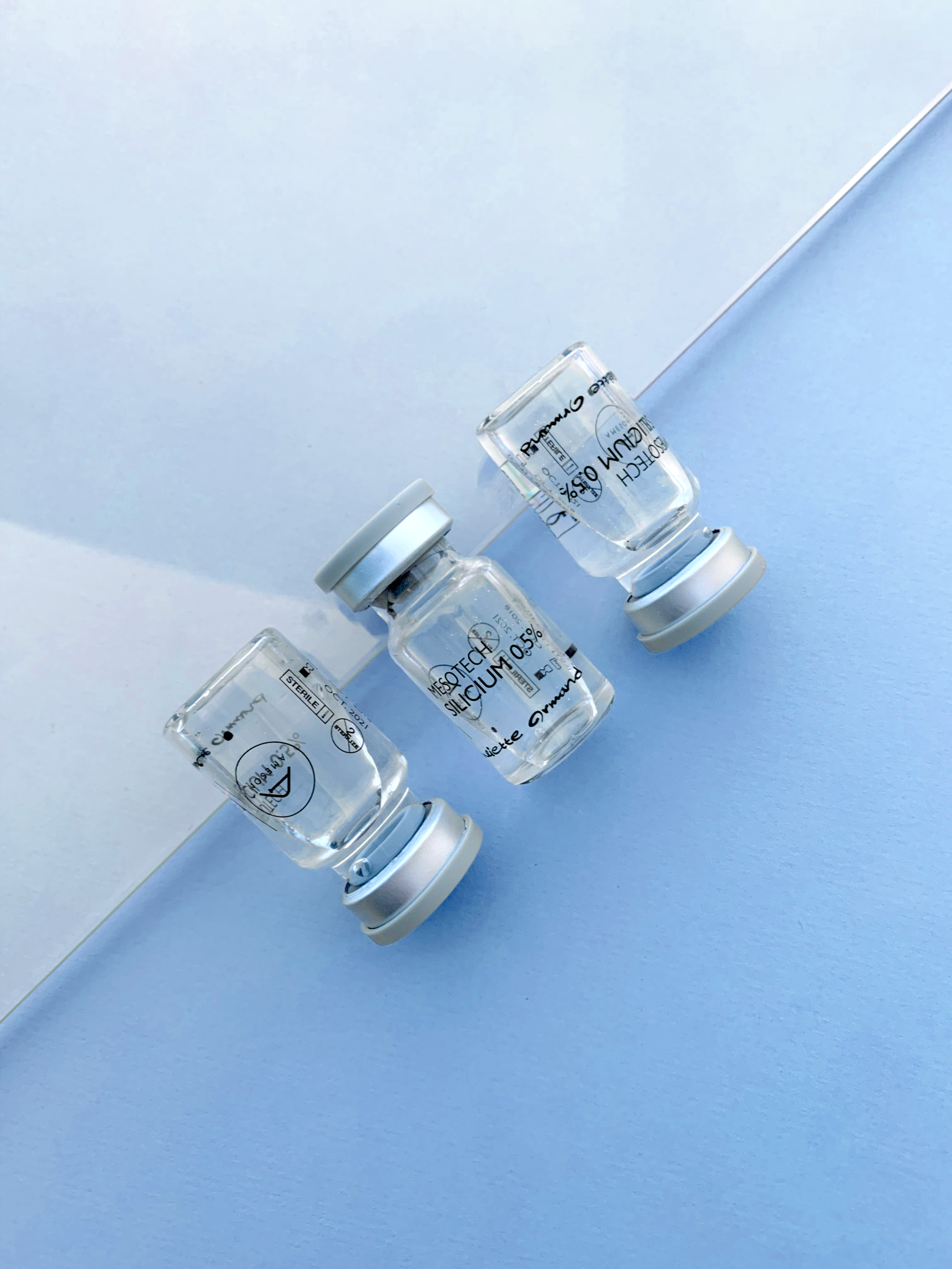 A minimalist top view of transparent medical vials on a light blue surface. Perfect for healthcare content.
